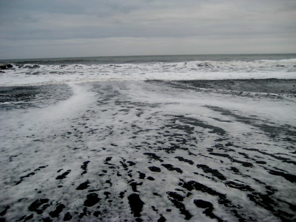 The ocean crashes over the black sand beach of Vik.